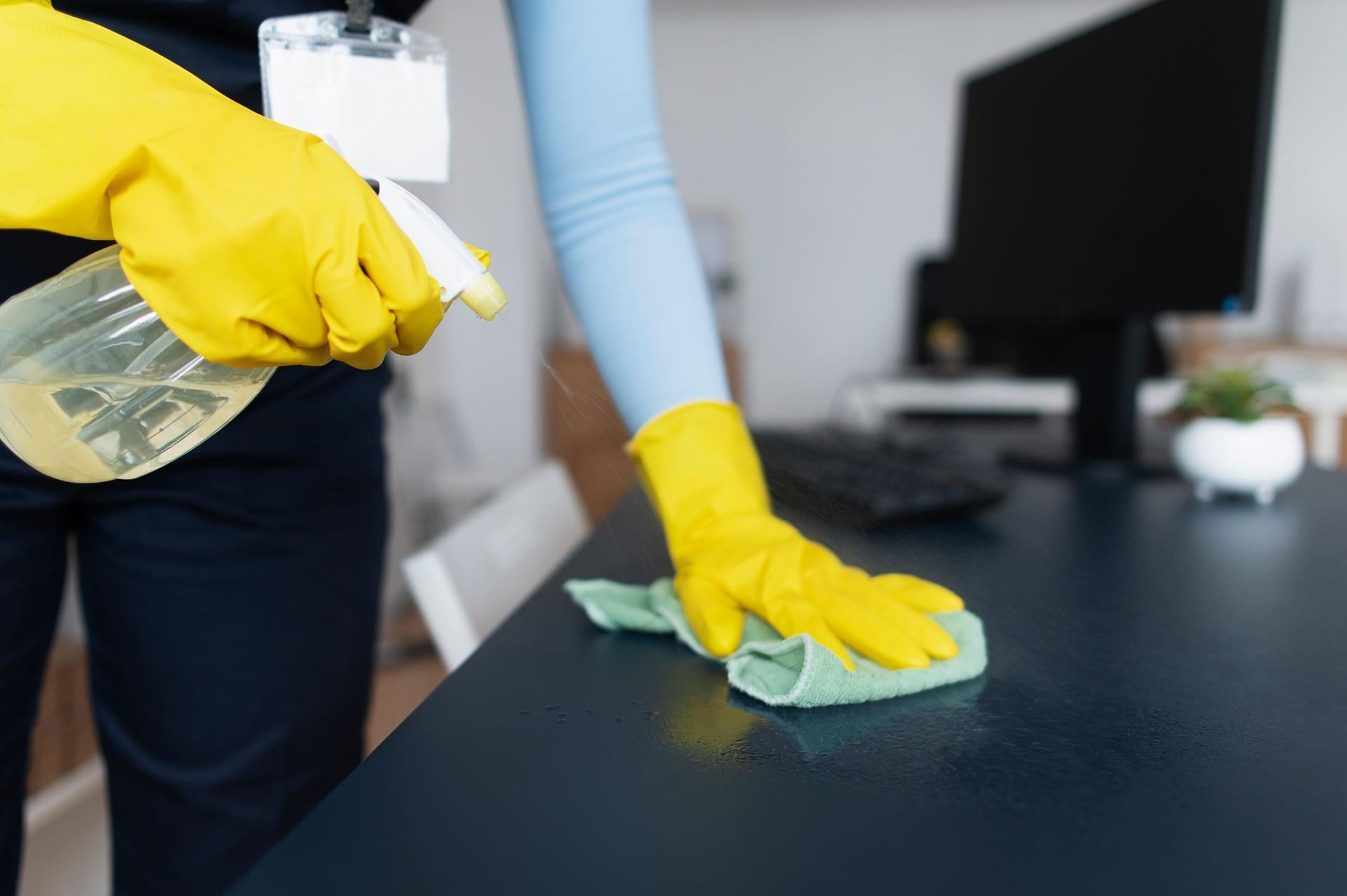 Janitor disinfecting office desk as part of commercial office cleaning services to maintain a clean and healthy workspace